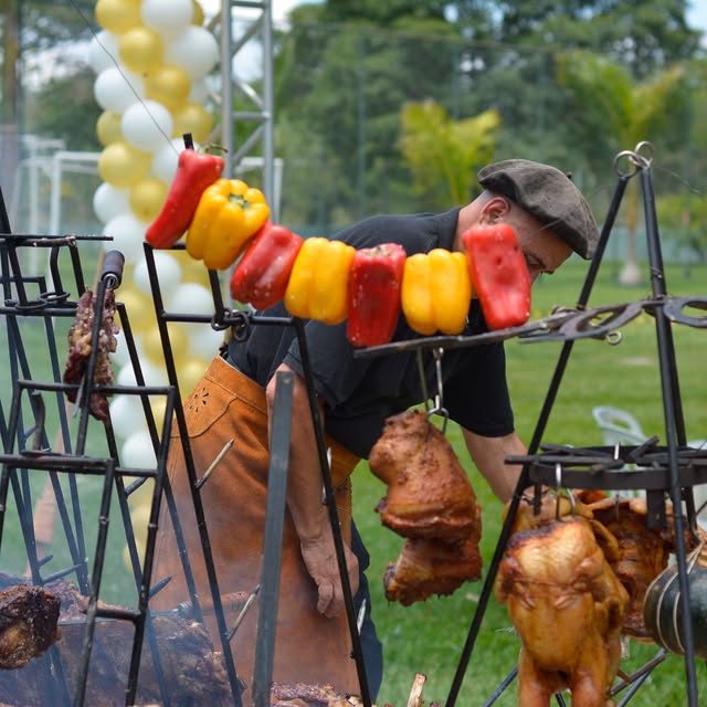 Assador cuidando dos espetos de pimentão, frango e carnes em um evento ao ar livre