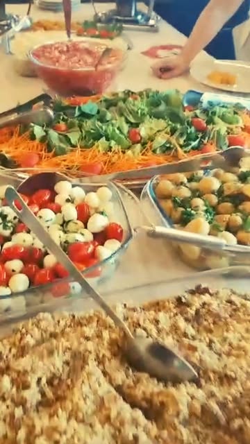 Mesa de saladas do buffet com caprese, folhas e farofa